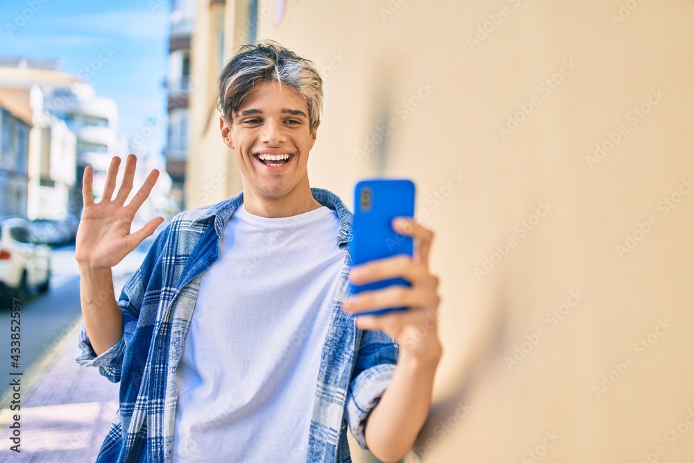 Young hispanic man smiling happy doing video call using smartphone at the city. Young hispanic man smiling happy doing video call using smartphone at the city.