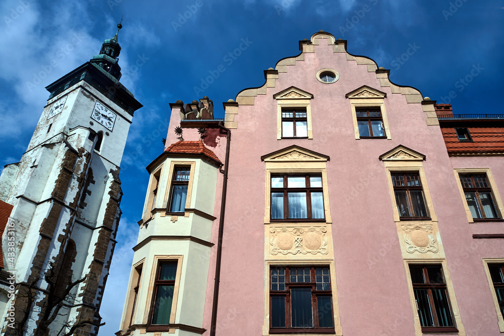 The facade of a historic tenement house and the belfry of a medieval church in the town of Zlotoryja
