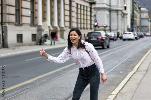 Shallow focus of a young cheerful woman catching a taxi on the street in Bosnia and Herzegovi photo