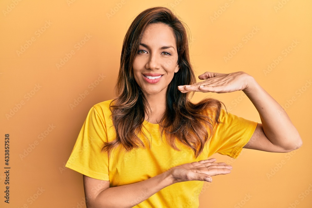 Young latin woman wearing casual clothes gesturing with hands showing big and large size sign, measure symbol. smiling looking at the camera. measuring concept. Young latin woman wearing casual clothes gesturing with hands showing big and large size sign, measure symbol. smiling looking at the camera. measuring concept.