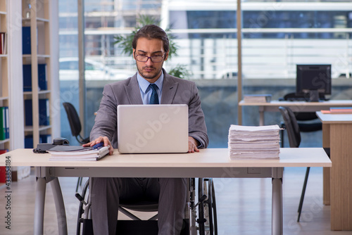 Young male employee in wheel-chair working in the office © Elnur