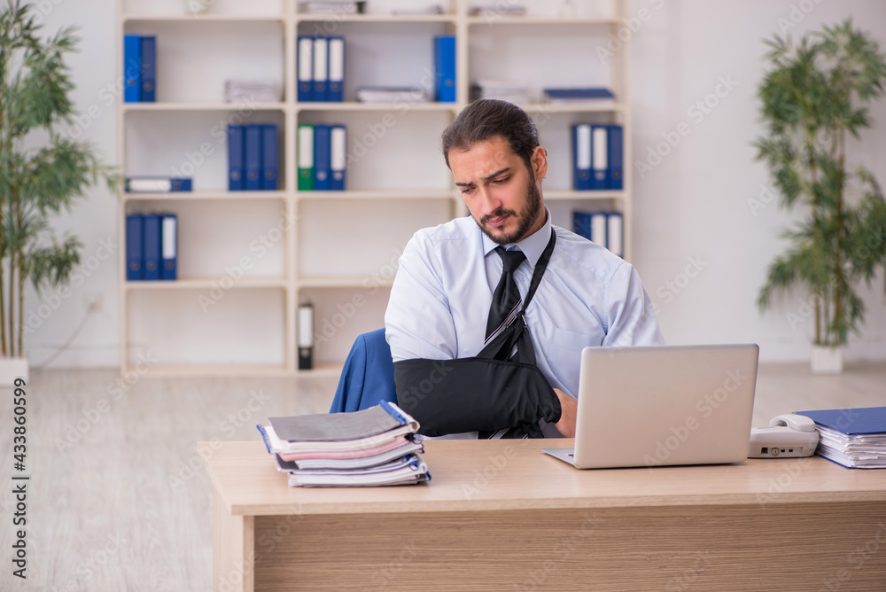 Young arm injured male employee working in the office Young arm injured male employee working in the office