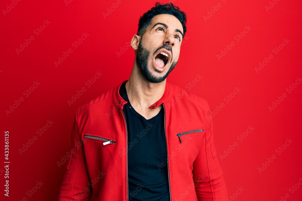 Young hispanic man wearing red leather jacket angry and mad screaming frustrated and furious, shouting with anger. rage and aggressive concept. Young hispanic man wearing red leather jacket angry and mad screaming frustrated and furious, shouting with anger. rage and aggressive concept.