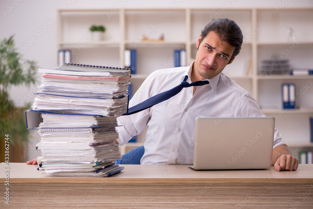 Young male employee and a lot of work in the office Young male employee and a lot of work in the office