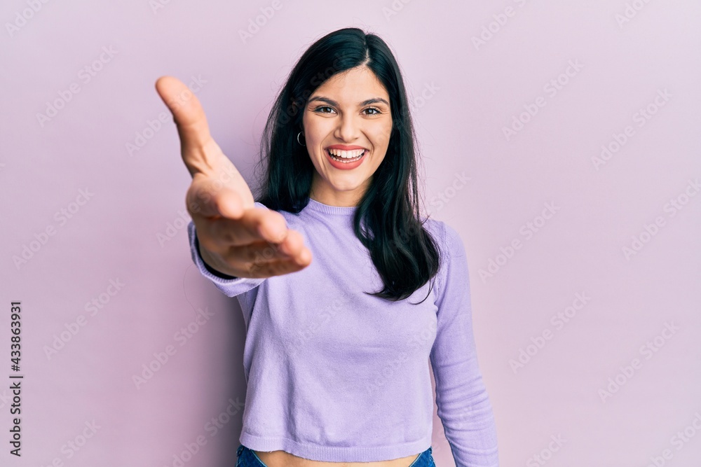 Young hispanic woman wearing casual clothes smiling friendly offering handshake as greeting and welcoming. successful business. Young hispanic woman wearing casual clothes smiling friendly offering handshake as greeting and welcoming. successful business.