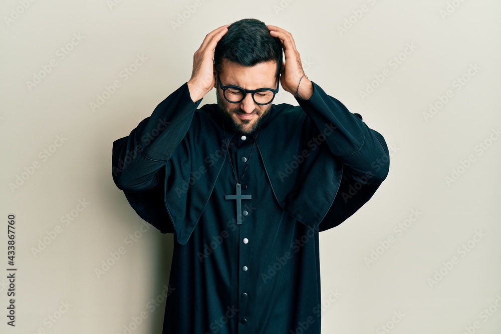 Young hispanic man wearing priest uniform standing over white background suffering from headache desperate and stressed because pain and migraine. hands on head. Young hispanic man wearing priest uniform standing over white background suffering from headache desperate and stressed because pain and migraine. hands on head.