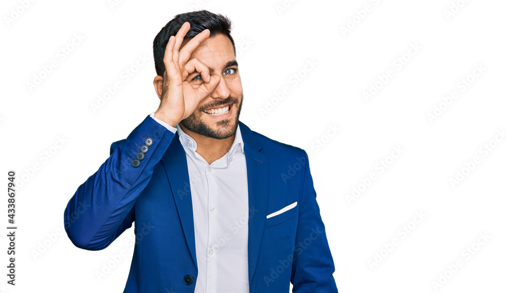 Young hispanic man wearing business jacket doing ok gesture with hand smiling, eye looking through fingers with happy face. Young hispanic man wearing business jacket doing ok gesture with hand smiling, eye looking through fingers with happy face.