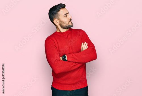 Young hispanic man wearing casual clothes looking to the side with arms crossed convinced and confident