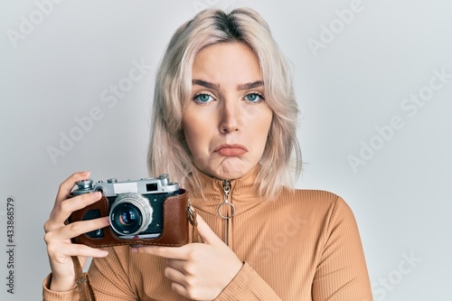 Valokuva Young blonde girl holding vintage camera depressed and worry for distress, crying angry and afraid
