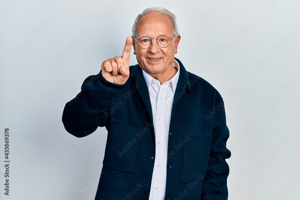 Senior man with grey hair wearing casual style and glasses showing and pointing up with finger number one while smiling confident and happy. Senior man with grey hair wearing casual style and glasses showing and pointing up with finger number one while smiling confident and happy.