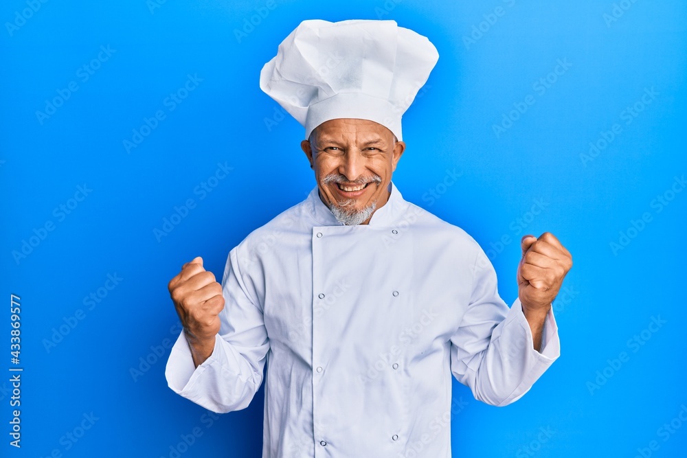 Middle age grey-haired man wearing professional cook uniform and hat excited for success with arms raised and eyes closed celebrating victory smiling. winner concept. Middle age grey-haired man wearing professional cook uniform and hat excited for success with arms raised and eyes closed celebrating victory smiling. winner concept.