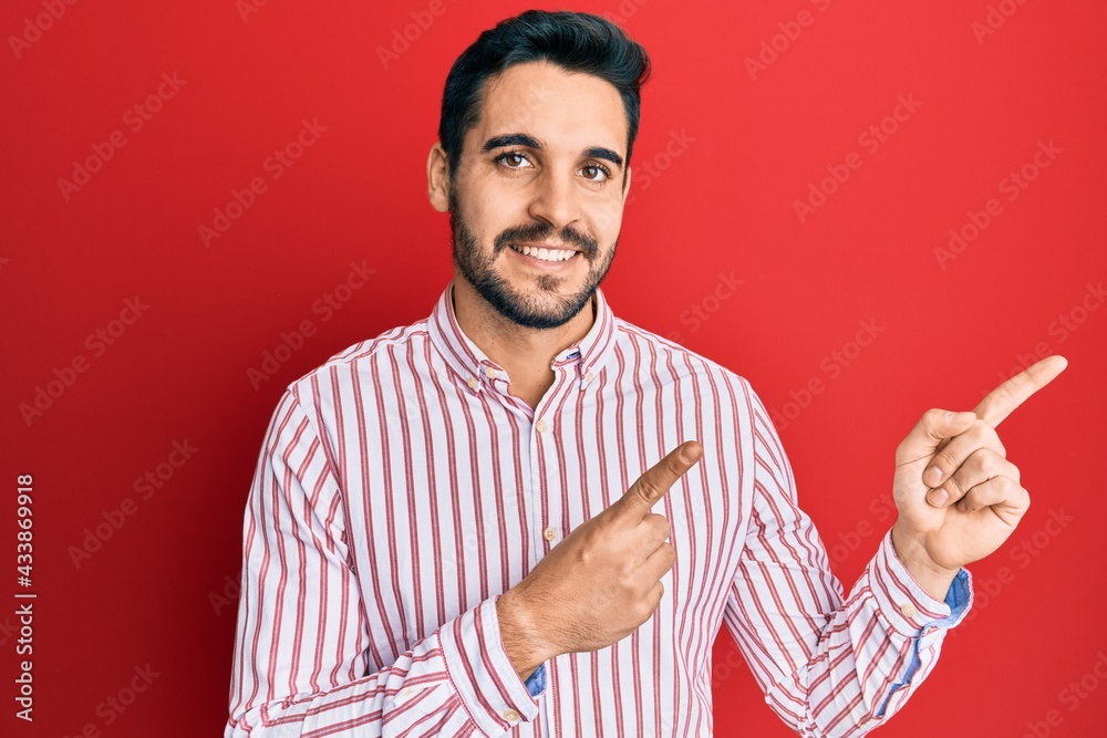 Fototapeta premium Young hispanic man wearing business shirt smiling and looking at the camera pointing with two hands and fingers to the side.