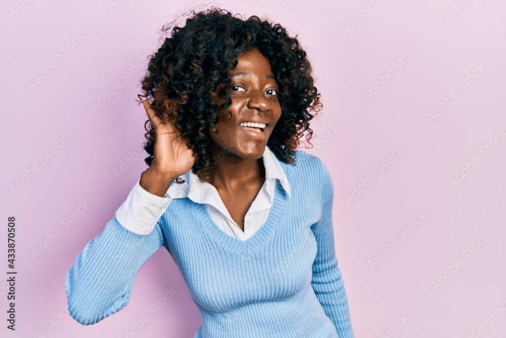 Young african american woman wearing casual clothes smiling with hand over ear listening and hearing to rumor or gossip. deafness concept. Young african american woman wearing casual clothes smiling with hand over ear listening and hearing to rumor or gossip. deafness concept.