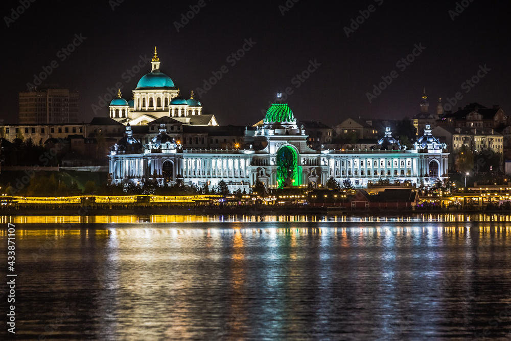 The beautifully illuminated embankment is reflected in the Kazanka River in the city of Kazan on a clear warm summer night