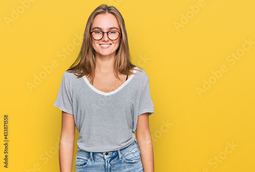 Beautiful young blonde woman wearing casual clothes and glasses with a happy and cool smile on face. lucky person.