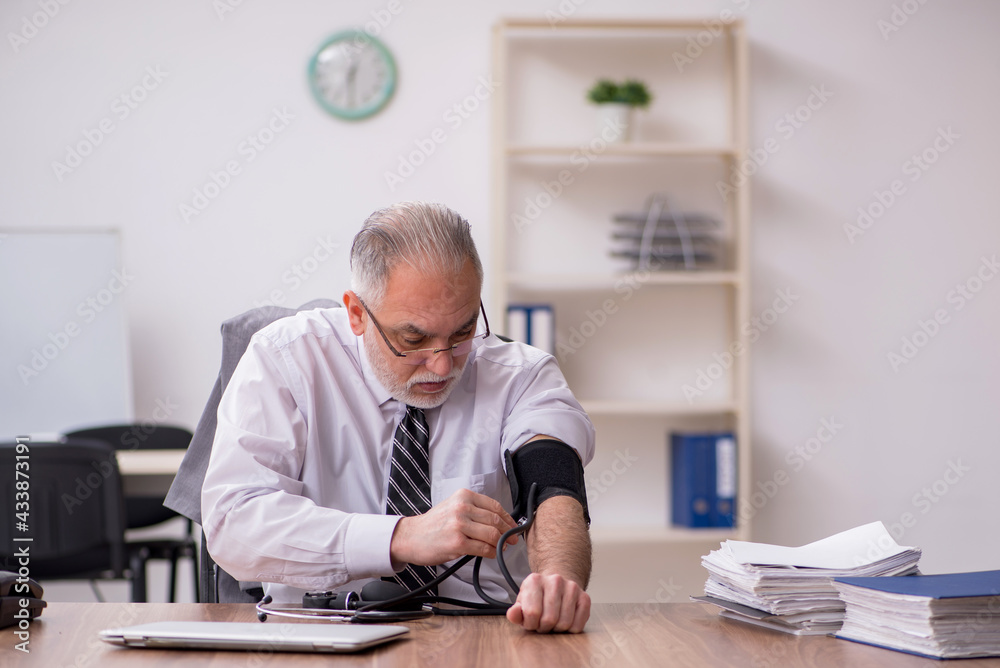 Aged male employee suffering at workplace Aged male employee suffering at workplace