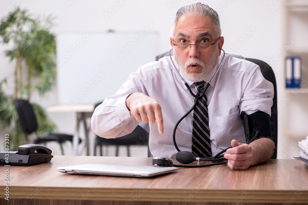 Aged male employee suffering at workplace Aged male employee suffering at workplace