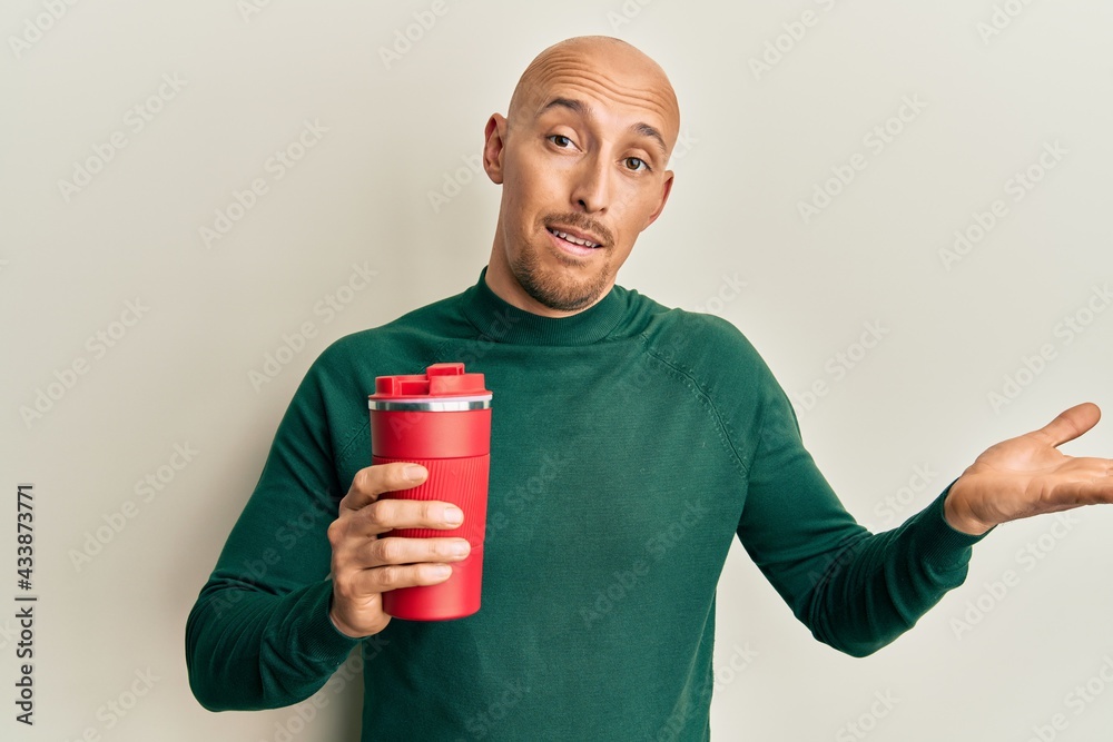 Bald man with beard drinking a take away cup of coffee celebrating achievement with happy smile and winner expression with raised hand Bald man with beard drinking a take away cup of coffee celebrating achievement with happy smile and winner expression with raised hand