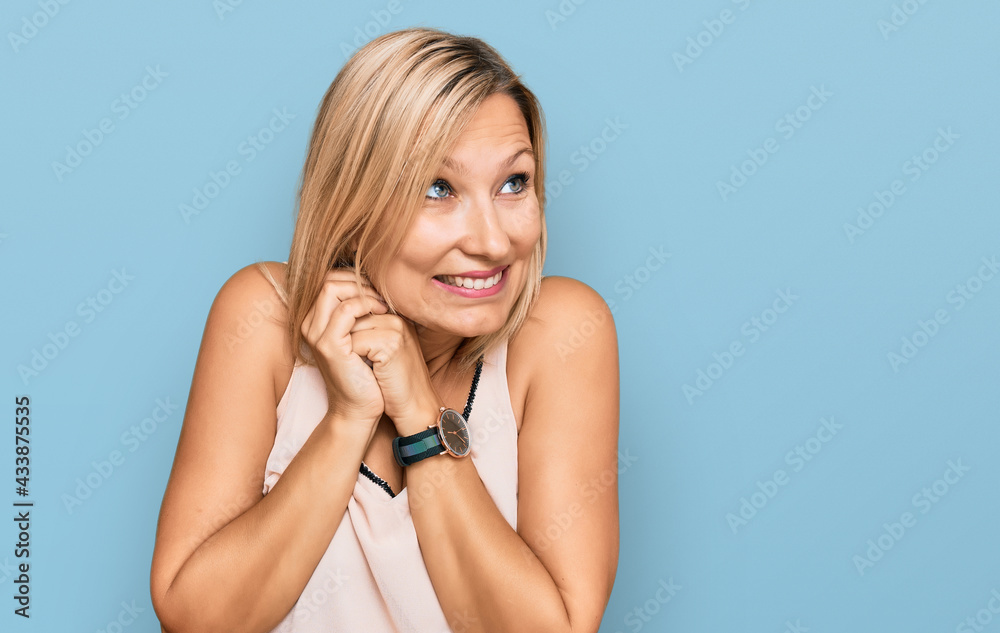 Middle age caucasian woman wearing casual clothes laughing nervous and excited with hands on chin looking to the side Middle age caucasian woman wearing casual clothes laughing nervous and excited with hands on chin looking to the side