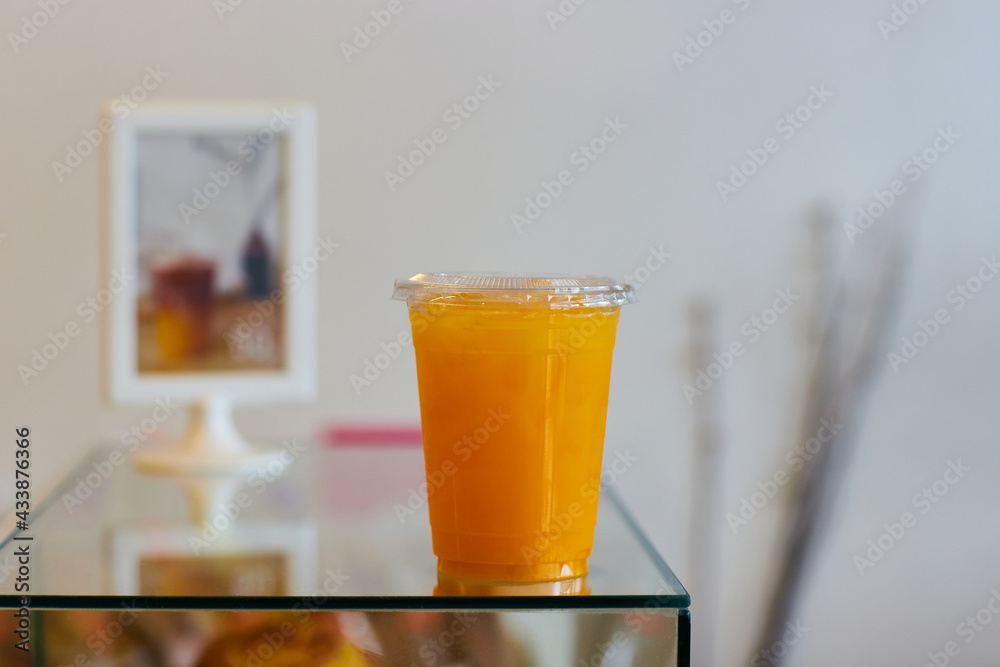 Plastic cup of orange juice and orange on table Plastic cup of orange juice and orange on table