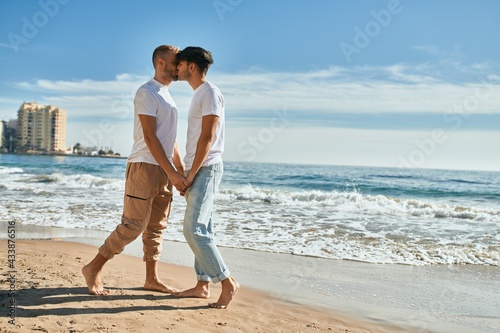 Young gay couple kissing at the beach.