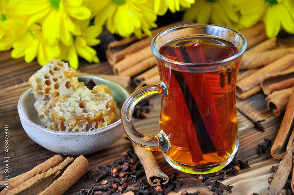 Tea with cinnamon, honeycomb on the table against the background of yellow chrysanthemums. Tea with cinnamon, honeycomb on the table against the background of yellow chrysanthemums.