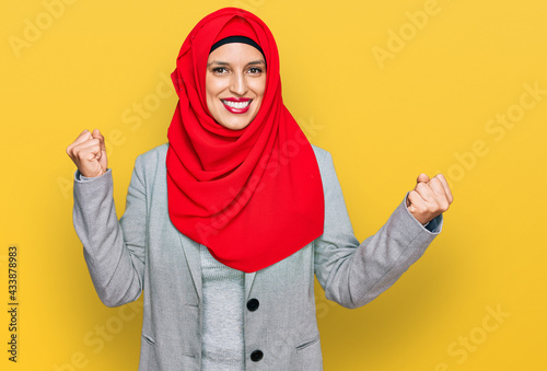 Beautiful hispanic woman wearing traditional islamic hijab scarf screaming proud, celebrating victory and success very excited with raised arms