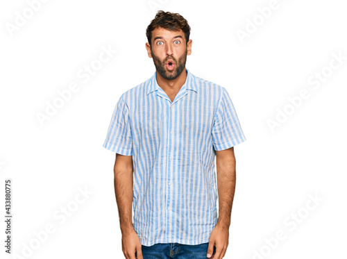 Handsome young man with beard wearing casual fresh shirt afraid and shocked with surprise expression, fear and excited face.