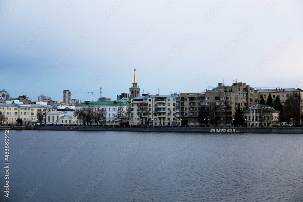View from the embankment to the evening city. City landscape on the river bank