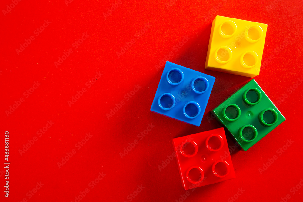 Color plastic building blocks on red background Color plastic building blocks on red background