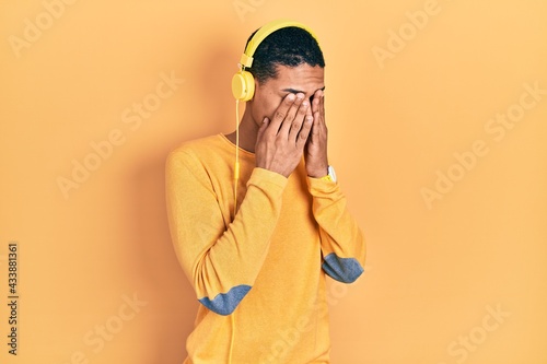 Young african american guy listening to music using headphones rubbing eyes for fatigue and headache, sleepy and tired expression. vision problem
