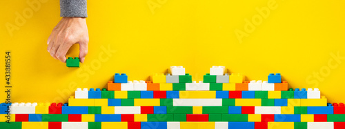 Quadro su tela hand building up a wall by stacking up plastic block