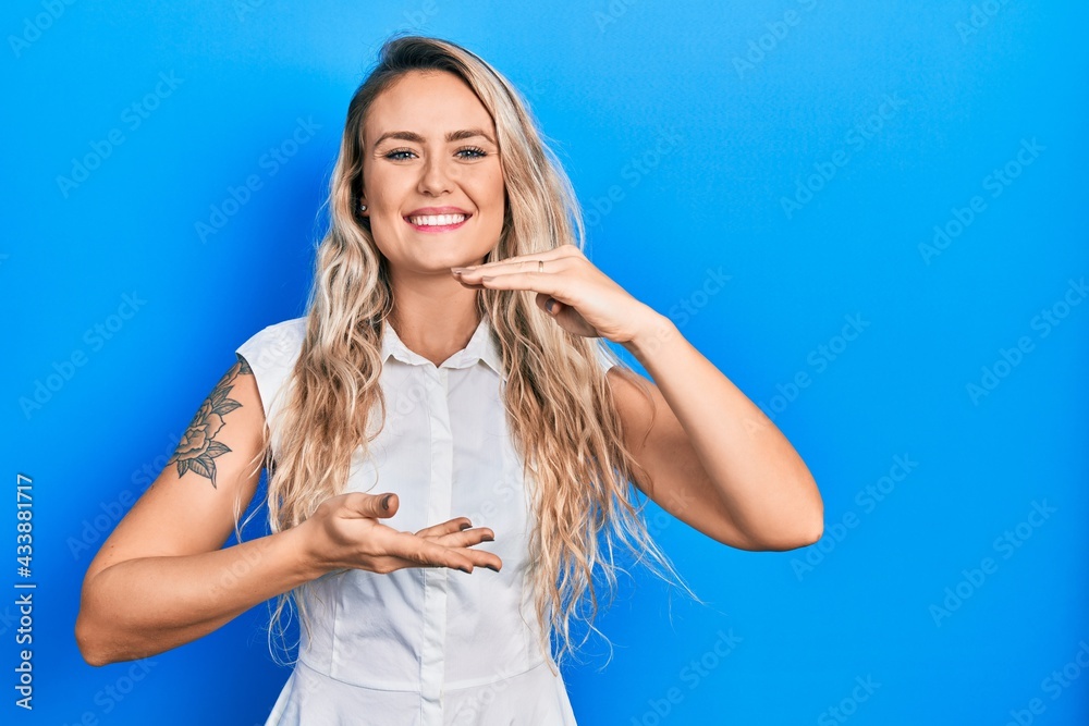 Beautiful young blonde woman wearing casual white shirt gesturing with hands showing big and large size sign, measure symbol. smiling looking at the camera. measuring concept.