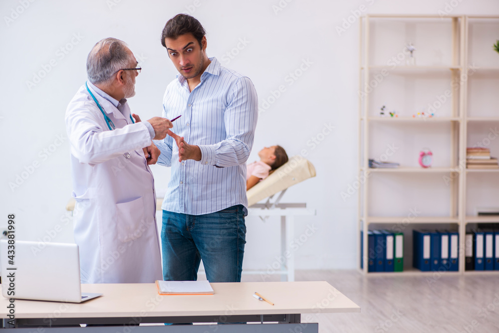 Small girl with her father visiting old male doctor Small girl with her father visiting old male doctor
