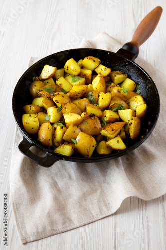 Homemade Roasted Potatoes with Mustard Seeds in a cast-iron pan, low angle view.