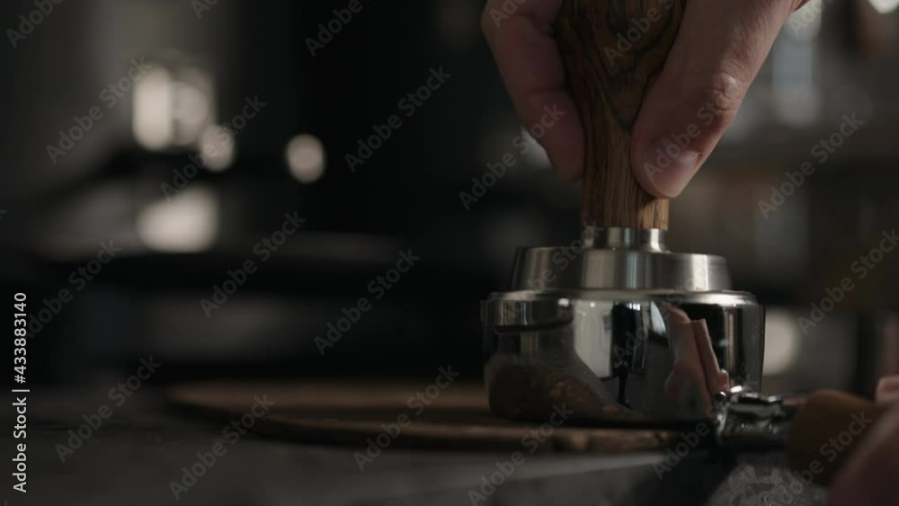 Slow motion closeup of barista spreading and tamping fresh coffee in bottomless portafilter Slow motion closeup of barista spreading and tamping fresh coffee in bottomless portafilter