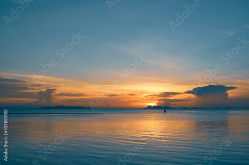 Silhouettes of people walking on the summer beach at sunset 