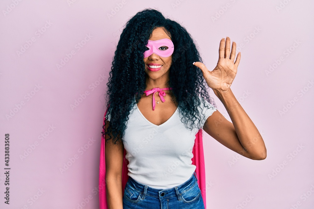 Middle age african american woman wearing super hero costume showing and pointing up with fingers number five while smiling confident and happy. Middle age african american woman wearing super hero costume showing and pointing up with fingers number five while smiling confident and happy.