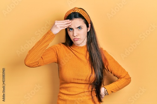 Young brunette teenager wearing casual yellow sweater worried and stressed about a problem with hand on forehead, nervous and anxious for crisis © Krakenimages.com