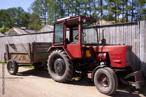 photo of old vintage red tractor. Vintage tractor by barn