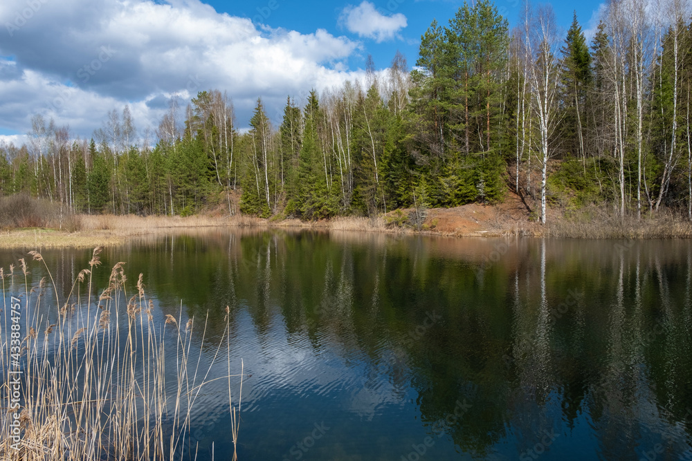 A small lake with high steep banks on a sunny spring day.
