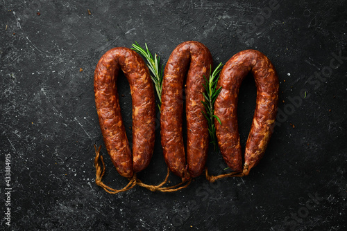 Smoked homemade sausage ring. Sausage on a black stone background. Top view.