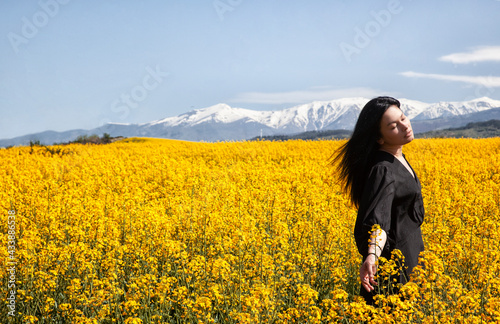 A beautiful girl in a black dress stands in the field. Spring photos