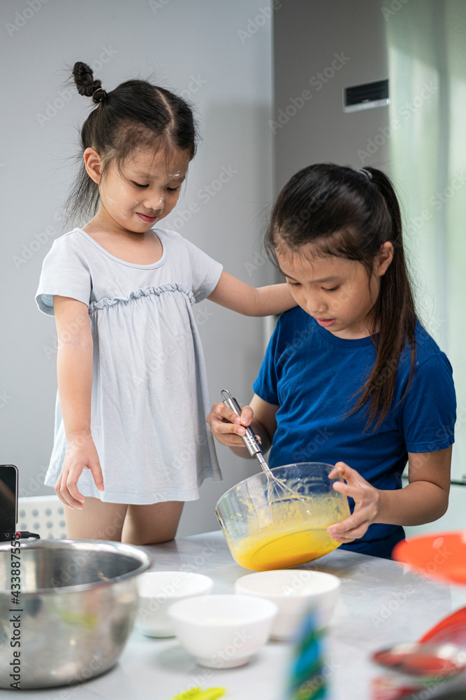 Happy family, little cute Asian girl preparation and baking cake in kitchen. lifestyle, homemade and baking concept