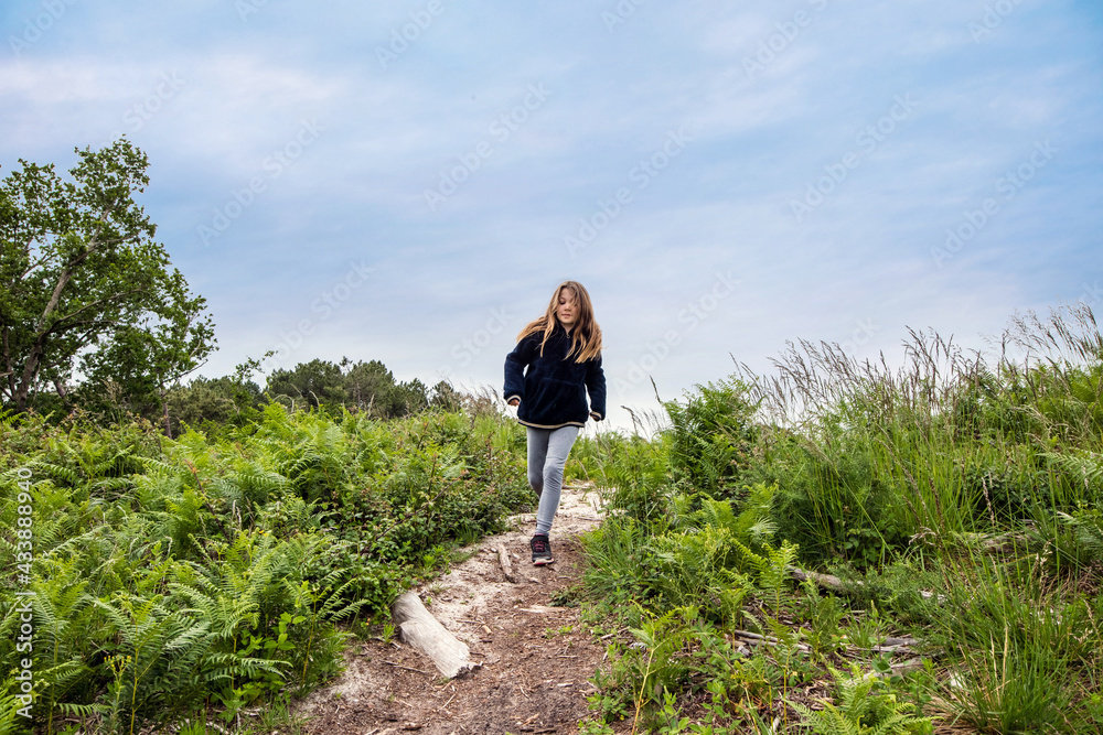 cute young girl running and jumping in a beautiful forest