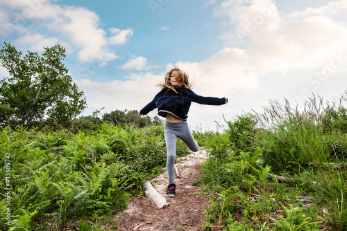 cute young girl running and jumping in a beautiful forest