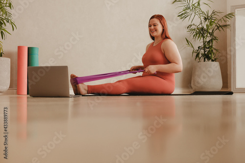 Leinwand Poster Fit woman watching video and doing stretching workout