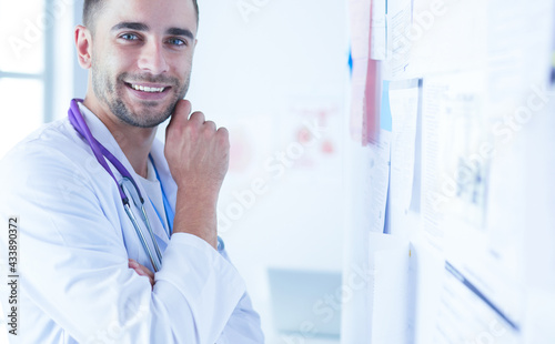 Young and confident male doctor portrait standing in medical office. photo