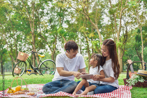 Portrait of happy Asian family, parents and daughter enjoying picnic meal in garden.Asian, Asian family, picnic, love, relationship, outdoors meal, park, family activities or happy garden concept