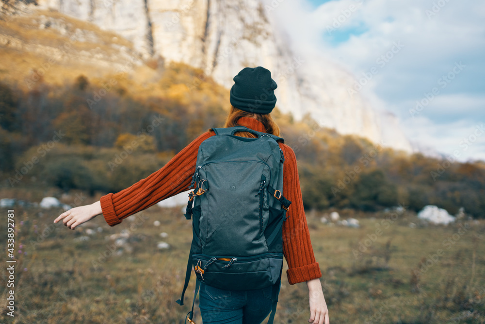 woman in a warm hat with a backpack on her back and in a sweater outdoors in the mountains gesticulate with her hands woman in a warm hat with a backpack on her back and in a sweater outdoors in the mountains gesticulate with her hands